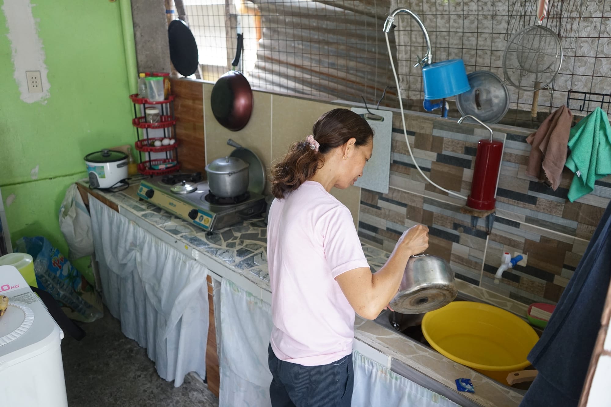 A photo of Rowela, a Watsi patient, working in the kitchen